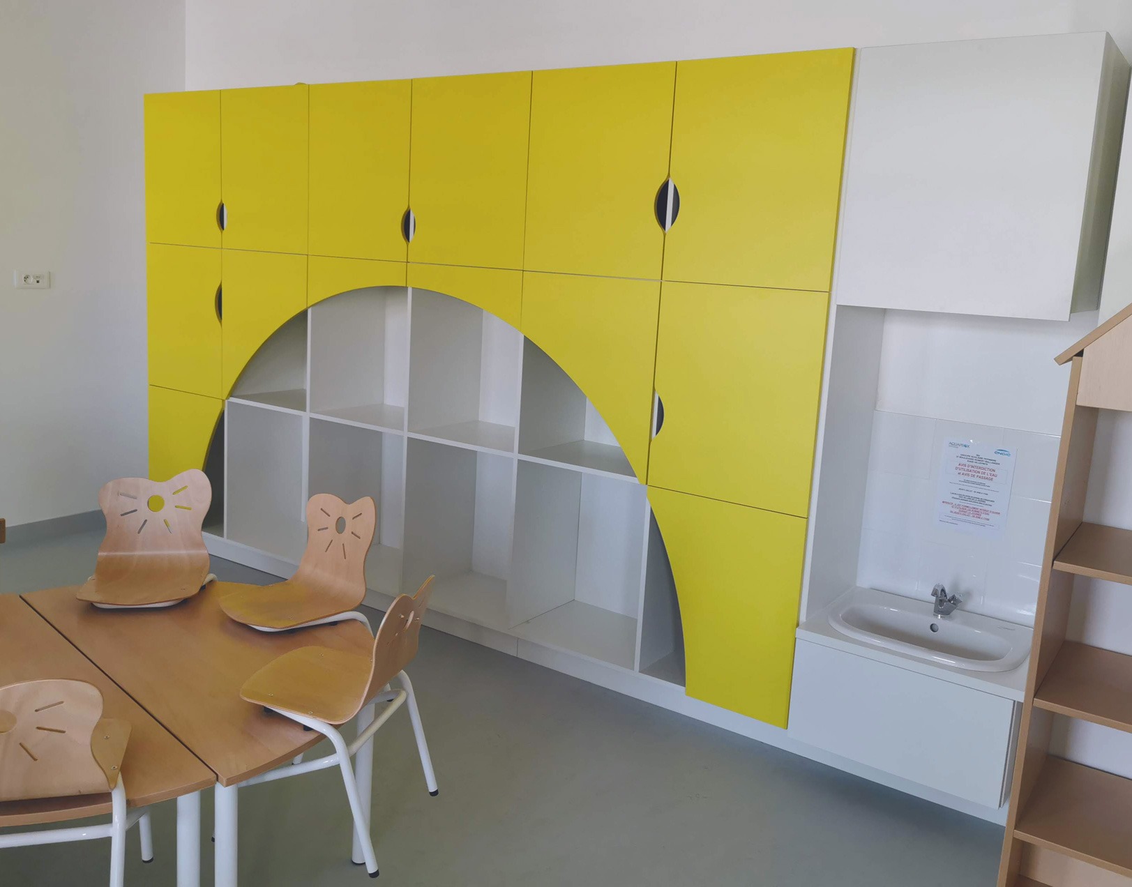 Aménagement d'une salle maternelle avec lavabo à hauteur et rangements incrustés